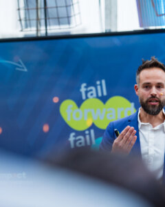 Een spreker tijdens de interne innovatiedag genaamd Impact Day, zijn presentatie leest 'fail forward'
