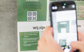 Een telefoon die een QR scant op een landbouwkalender voor meer informatie omtrent sociale rechten