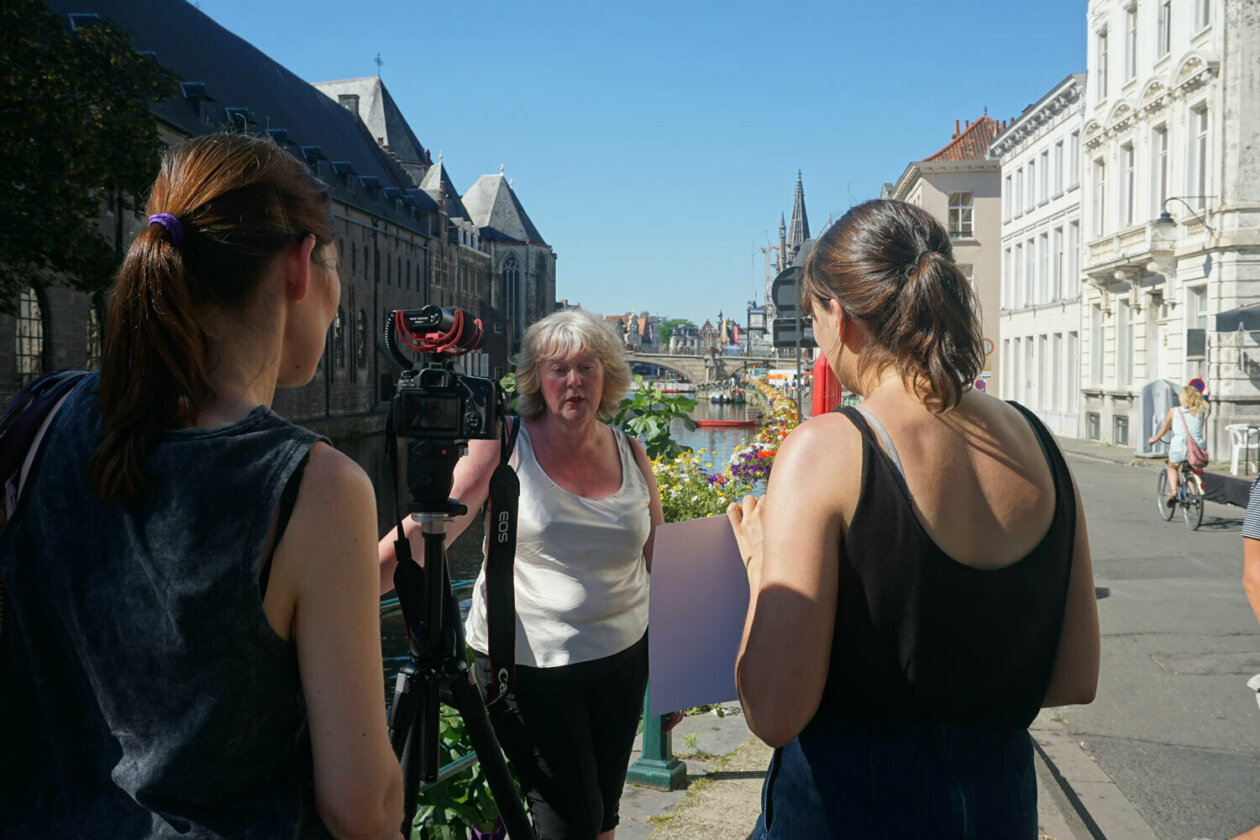 Two interviewers outside on a bridge in Ghent interviewing a lady with a camera for a qualitative user survey.
