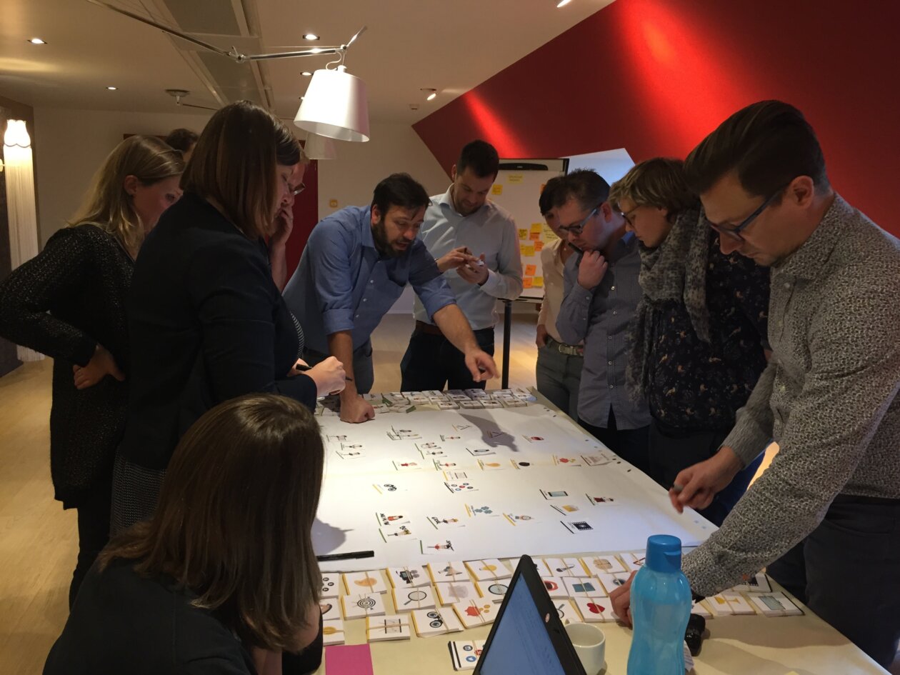 Voorbeeld van een co-creatie workshop waarbij de deelnemers rond een tafel staan en samen werken aan een stakeholdermap aan de hand van context kaarten.